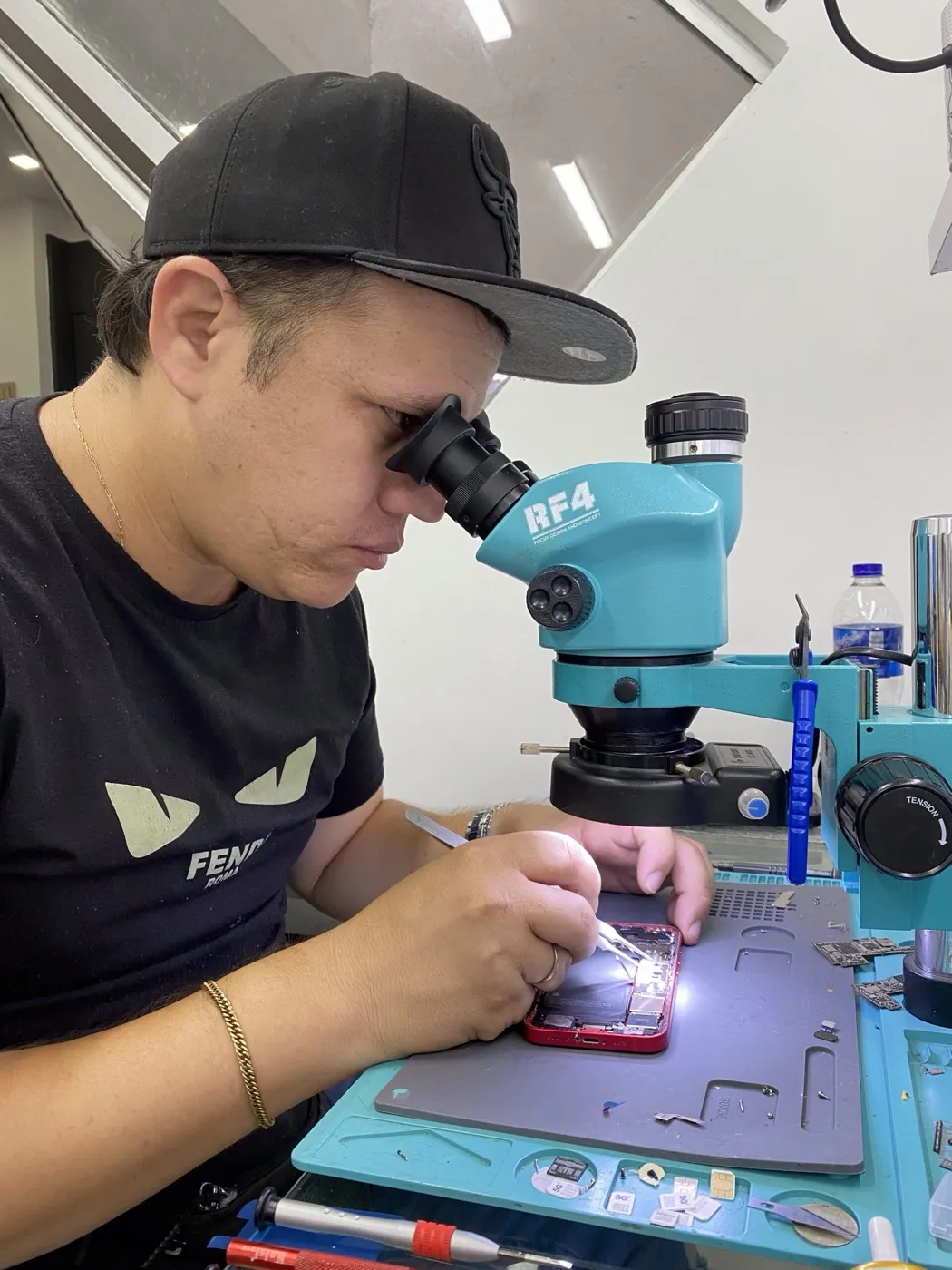 Estudiante de mobipLab Academy reparando una placa de celular bajo el microscopio
